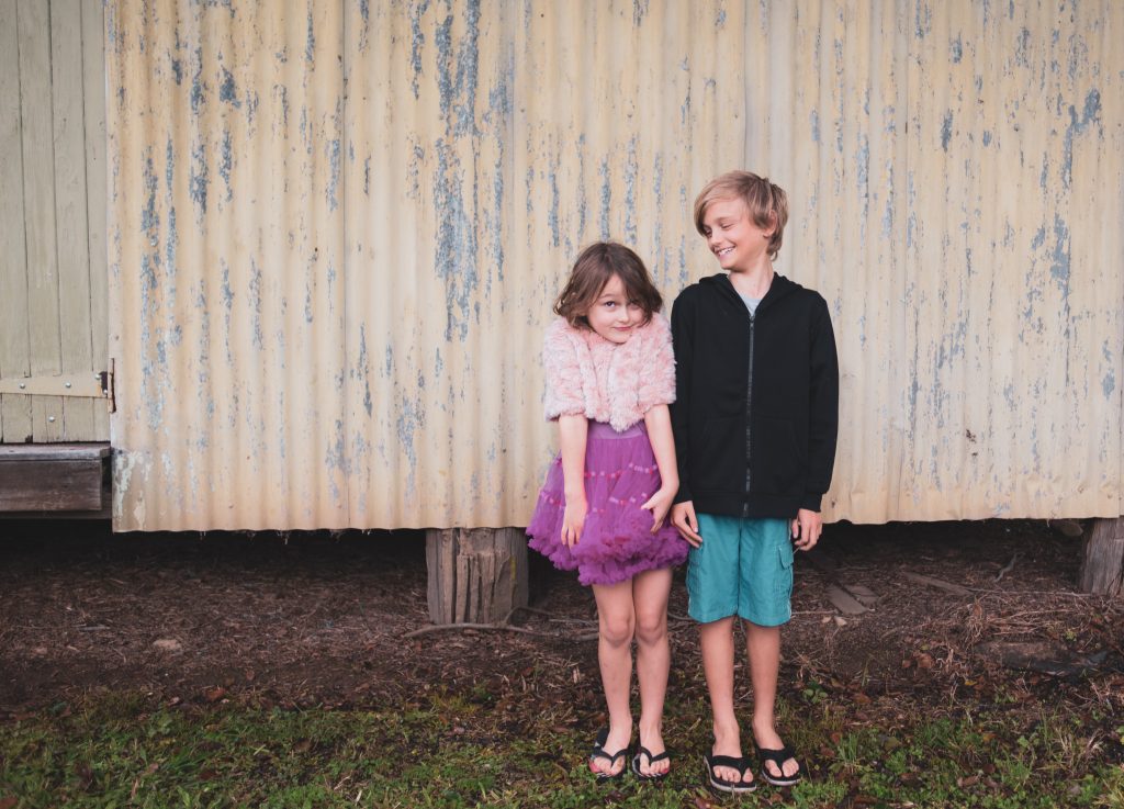 Two siblings standing in front of a house